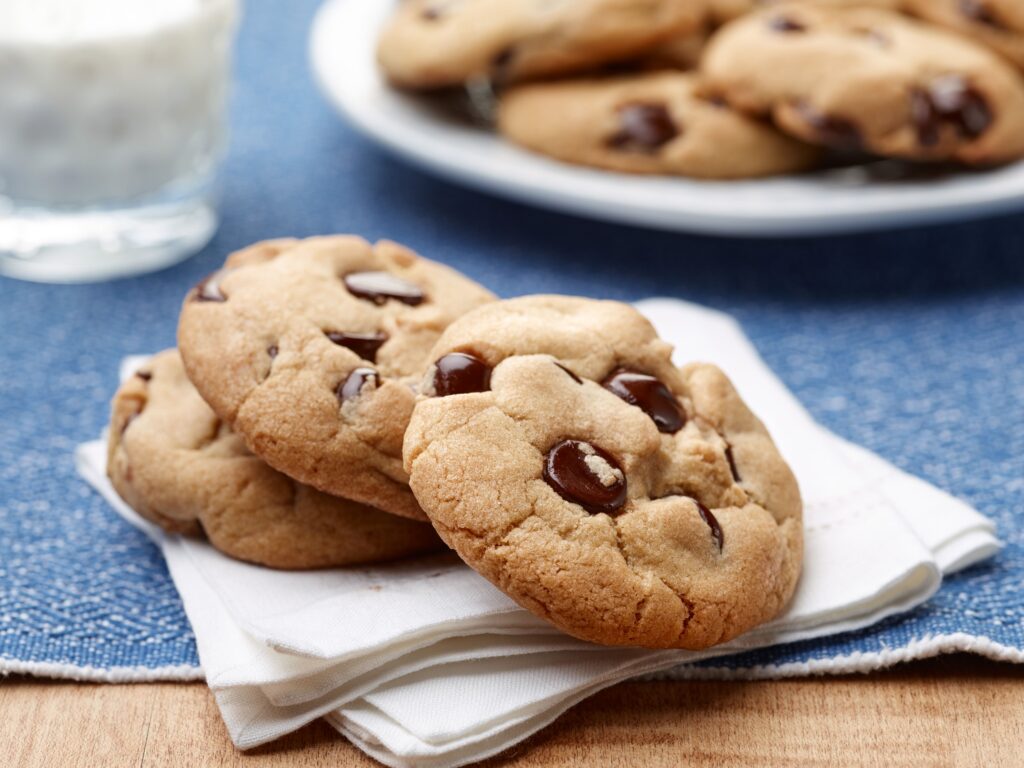 Freshly baked Nestle Toll House chocolate chip cookies cooling on a wire rack, showcasing golden edges and gooey chocolate morsels